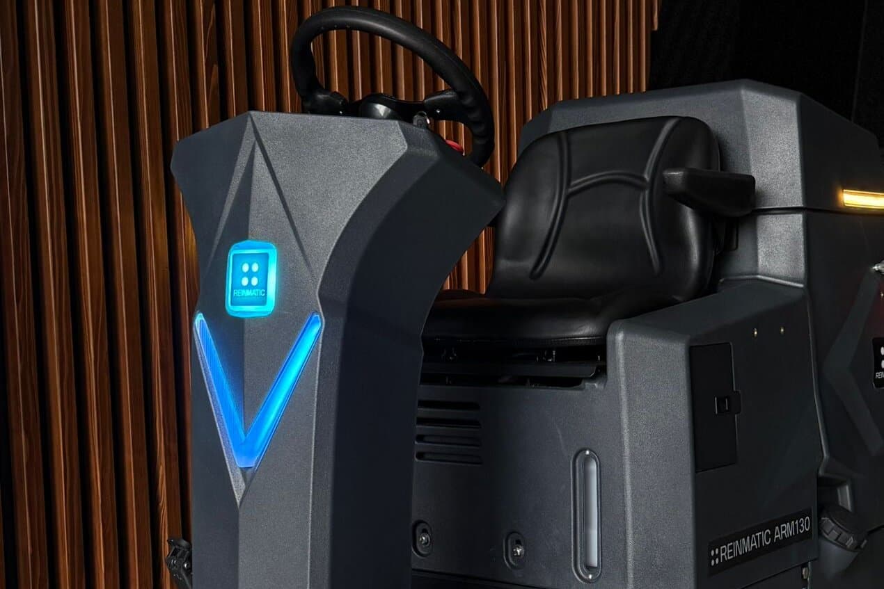 ARM 130 from the front three-quarter angle — blue V-shaped LED status column lit, steering wheel and operator seat visible