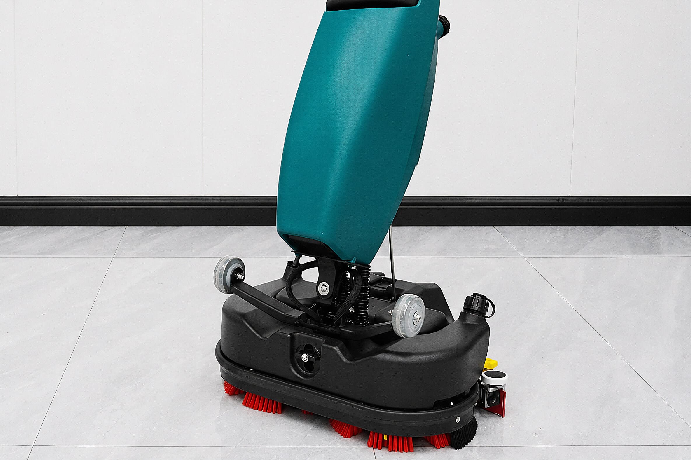 Reinmatic RM 5 at work on the stone floor of a modern building — rear three-quarter view with the brush deck on the tiles